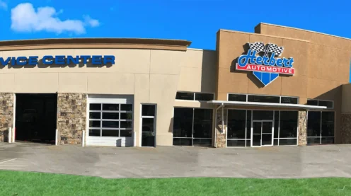 Exterior view of an automotive service center with multiple garage bays, a sign reading "Herbert Automotive" on the building, and clear primary navigation for customers arriving onsite.